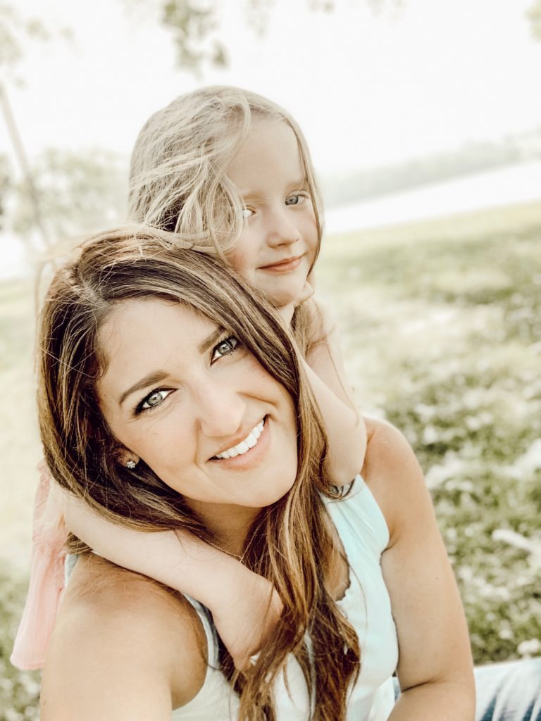 Happy mother with her toddler daughter on a summer lake day